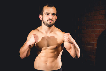 Fototapeta na wymiar Athlete standing in a boxing guard isolated with a dark background