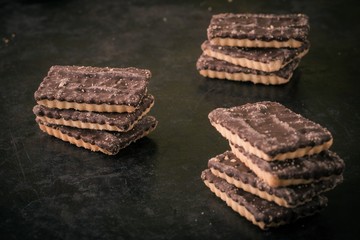Few chocolate biscuits in three stacks on black tray