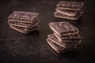 Few chocolate biscuits in three stacks on dark tray