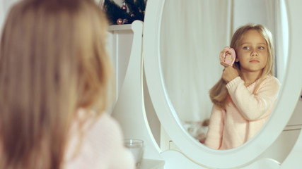 Fashionable little lady combing her hair and looking in the mirror