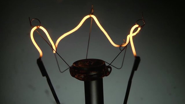 Dettaglio del filamento di una vecchia lampada al tungsteno che si accende e si spegne con intermittenza veloce.