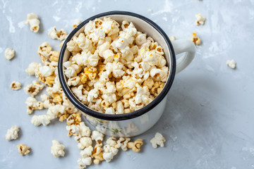 Sweet caramel popcorn in a large iron circle on the concrete gray background.