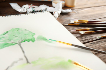 Brushes with album on wooden table