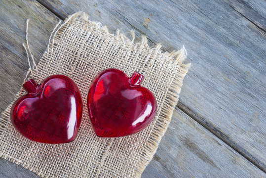 valentine's day concept/two red transparent hearts on sackcloth and old wooden background 