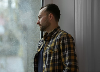 Handsome depressed man near window
