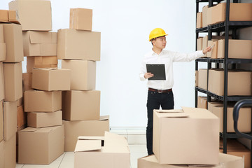 Man holding clipboard and pointing on cartoon box at warehouse