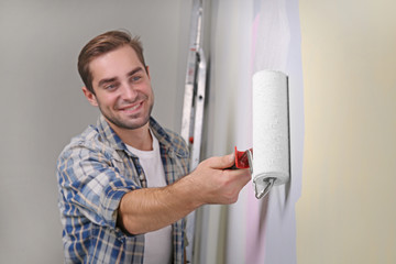 Handsome young man painting wall in room