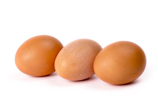 Три куриных коричневых яйца на белом фоне
