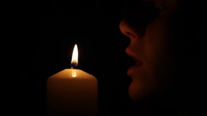 Woman blows out the candle in the dark
