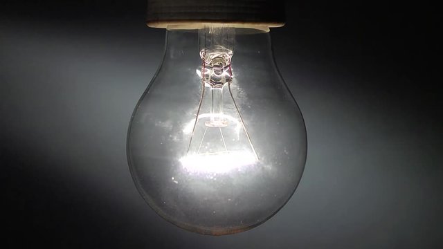 Una vecchia lampada al tungsteno in primo piano che si accende e si spegne con intermittenza veloce.