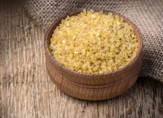 Raw Bulgur (on wooden background)