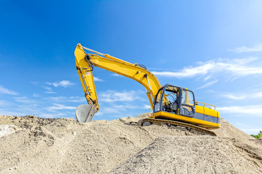 Excavator is preparing pile of sand for loading in truck on buil