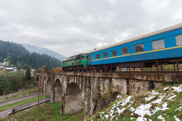 Fototapeta na wymiar Diesel train traveling on the viaduct. Vorokhta, Ukraine