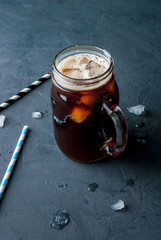 Iced coffee in a Mason Jar with straws and ice om the background. copy space