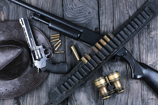 shotgun and a revolver, cartridge belt with bullets, wild west, cowboy, weathered wooden table