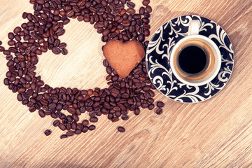 Heart make whit coffee beans and cup whit espresso and sweet heart cookie on wood table background. 