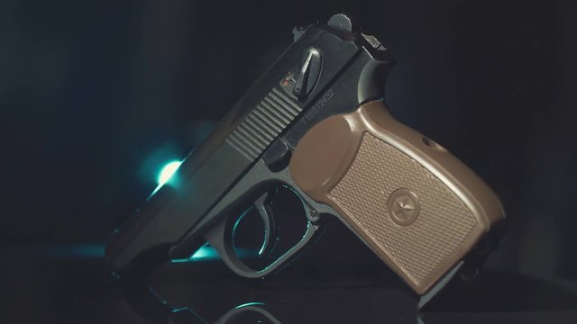 gun lies on the slowly rotating surface. Highlighted with by light.