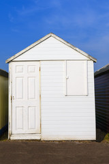 Old weathered white painted beach hut with blue sky background. Photographed in Shoeburyness, Essex