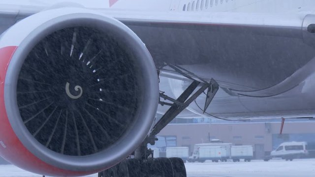 Plane parked at the airport. Ready to fly. The turbine close-up. In winter snow storm.