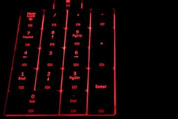 Computer keyboard with red illuminated buttons. Close up. 