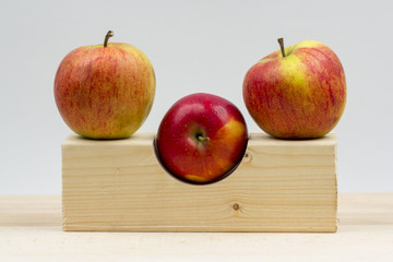 Wooden geometrical pieces with apples and light grey background