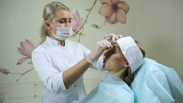 Non-surgical correction of shape of a nose. A young girl during a procedure. HD