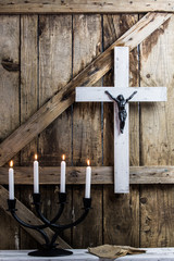 Wooden white cross, prayer and candles on a background of the old wooden walls