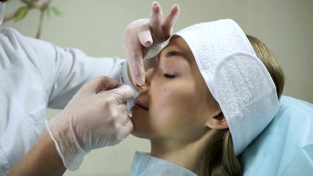 Non-surgical correction of shape of a nose. A young girl during a procedure. HD
