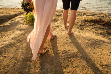 Fototapeta na wymiar Sea travel, couple walking on beach at hot summer weather. Legs of honeymooners or tourists on sea side