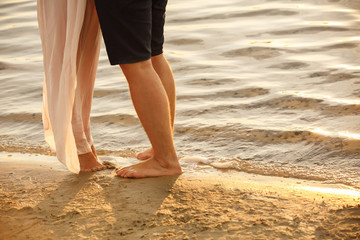 Sea or ocean resort, legs of couple on sea side at their honeymoon. Travel at summer time on beach