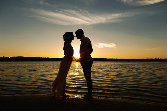Sea love, silhouette of young couple on sunset beach of sea or ocean. Honeymoon concept