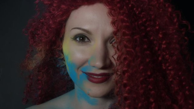 4k shoot of a redhead girl in studio with blue dust on her face
