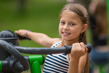 Ten-year girl doing exercises at a sports ground outdoors.