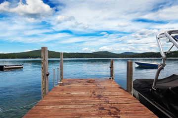 Wooden dock with a trail of wet footprints leading to a warm summer lake
