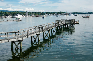 Fototapeta na wymiar Long Pier: A wooden walkway extends far across the shallow end of a bay in Maine. 