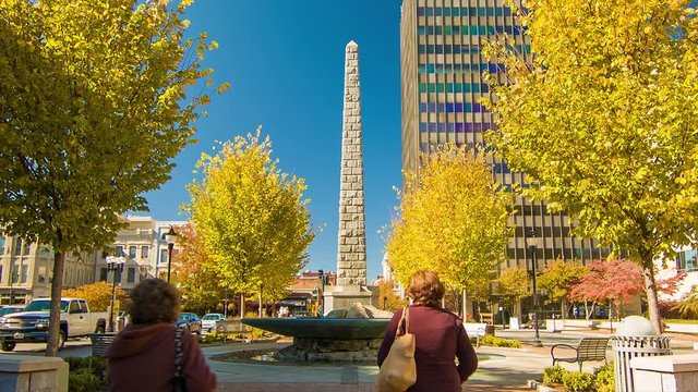Tourists Walking by the Vance Memorial in Asheville NC City Center on a Sunny Autumn Morning with Fall Colored Trees and a Blue Sky