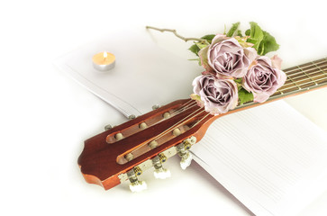 Guitar neck with roses and sheet music, on white