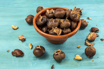 Roasted chestnuts in earthenware bowl on turquoise