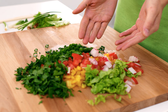 Close up of  woman's hands cooking in the kitchen. Housewife offering ​​fresh salad. Vegetarian and healthily cooking concept