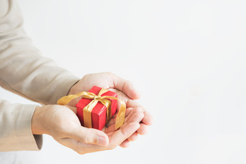 A man holding red gift box with golden ribbon, on white background with copy space