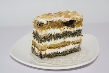 Cake with poppy seeds and cream on a white plate 