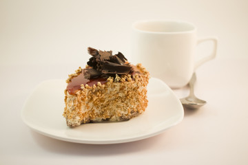 A cake with chocolate on a white plate with white tea Cup