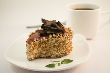 A cake with chocolate on a white plate with white tea Cup
