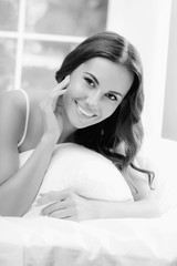 Young beautiful smiling woman waking up with pillow, at bedroom