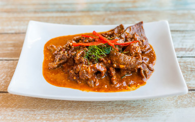 Beef in ground peanut coconut cream curry on white plate