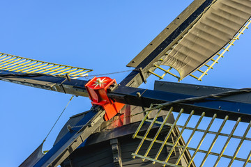 Red painted windmill cross with sails from close