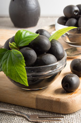 Black olives in a glass bowl on the vintage tablecloths and fork