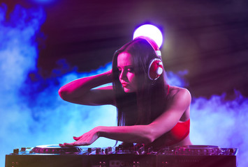 Fototapeta na wymiar Pretty young DJ playing music in nightclub