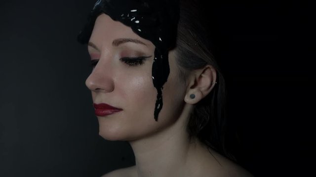 4k shoot of a model in studio with black mud pouring on her face