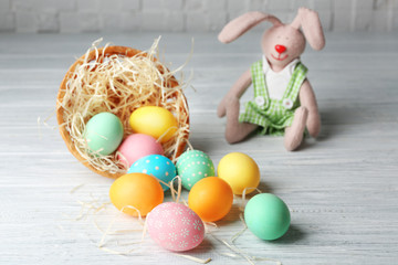 Fototapeta na wymiar Decorative nest with colorful Easter eggs and bunny on wooden table